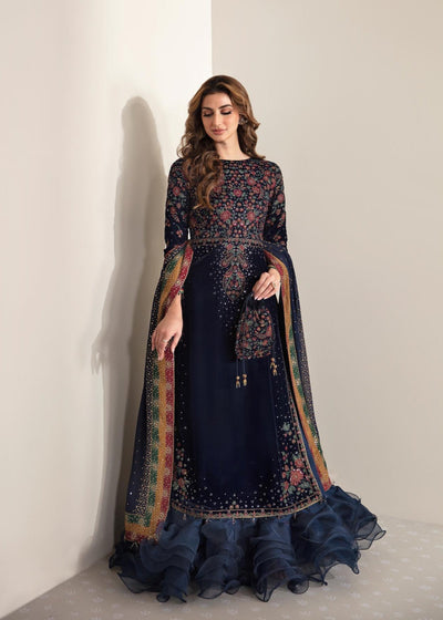 Woman wearing a dark blue embroidered traditional outfit with a patterned dupatta against a white background