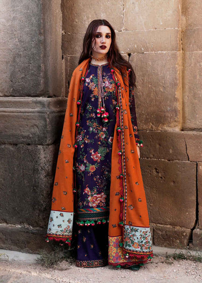 Woman wearing a traditional outfit with an orange dupatta against a stone wall.